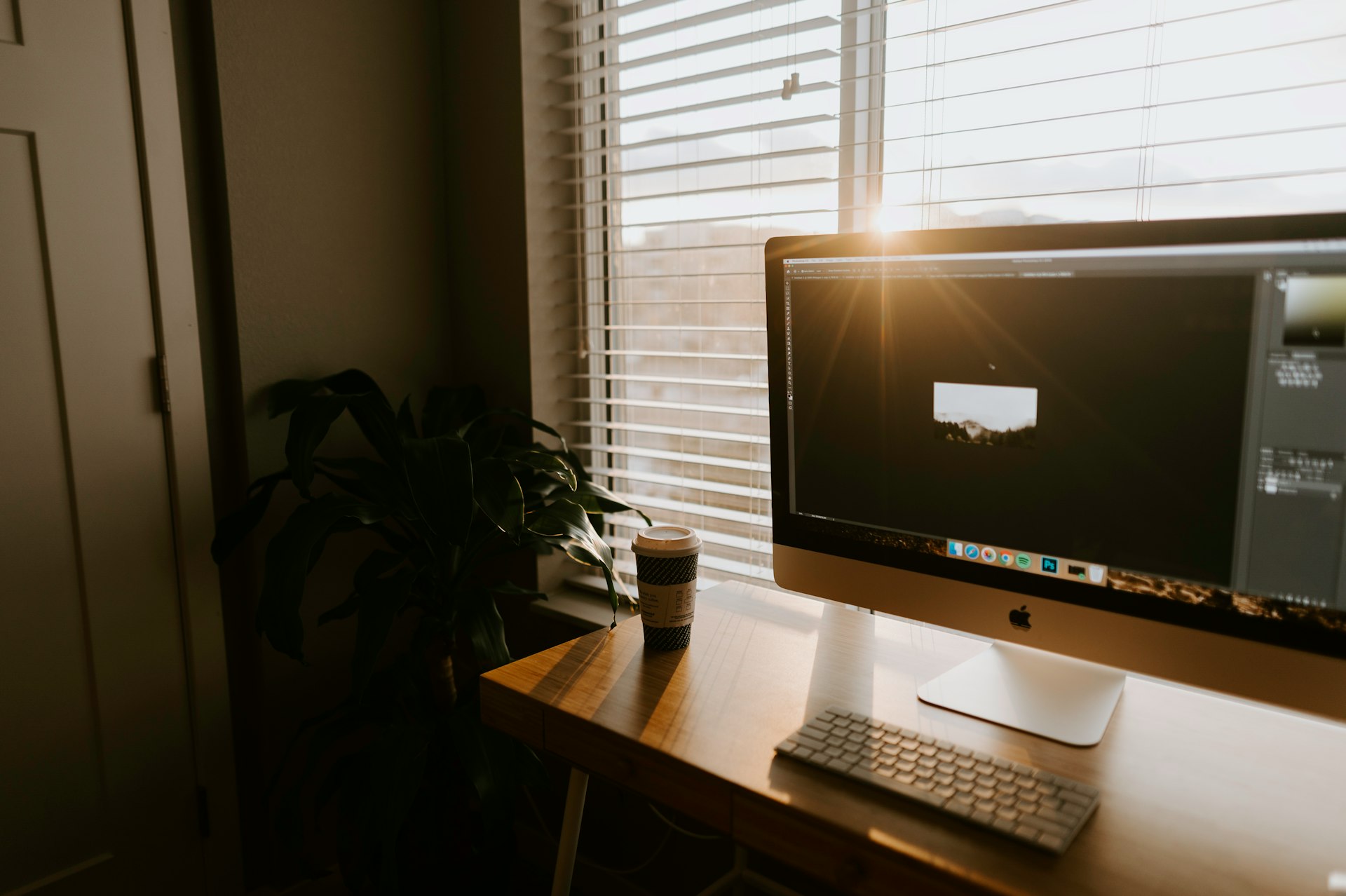 silver iMac on brown wooden table near closed door